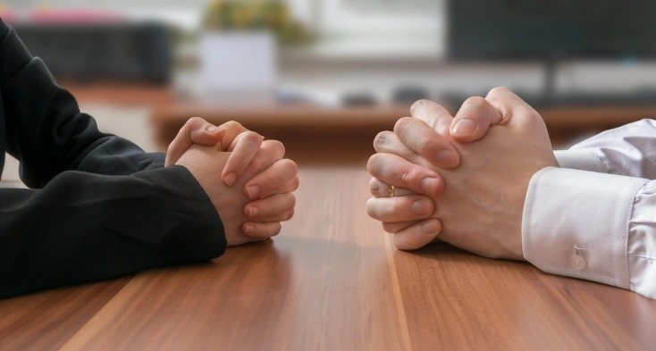 Two people’s hands resting on a table.