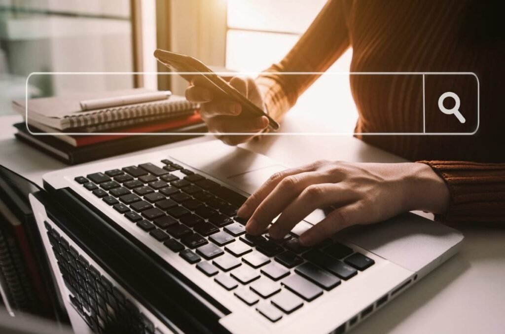 A person using a laptop and phone to search.