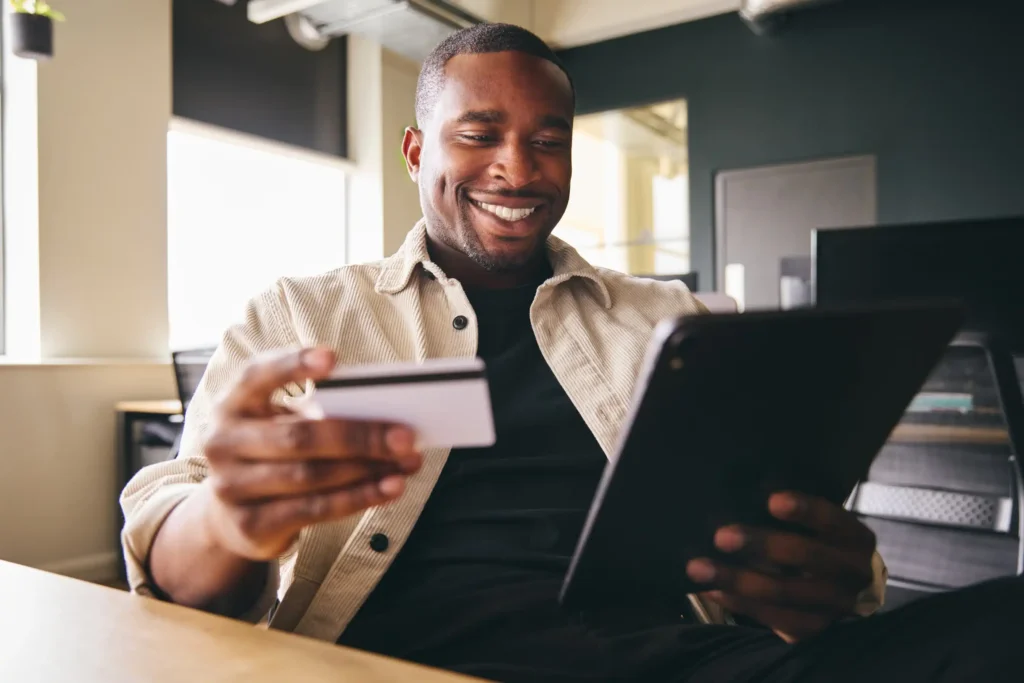 a person ia holding a payment card and looking at laptop screen