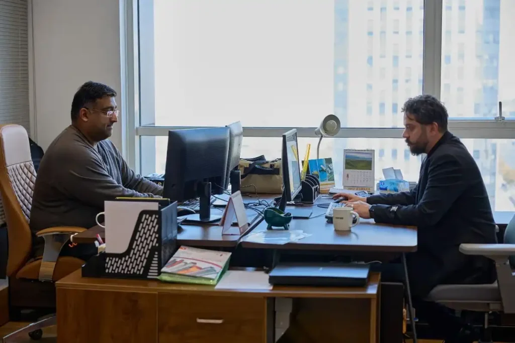 Two business professionals discussing sourcing and quality control processes in an office, showing a buyer consultation or problem-solving meeting.